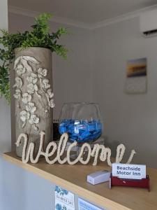 a welcome sign sitting on a shelf with a fish bowl at Beachside Motor Inn in Hervey Bay