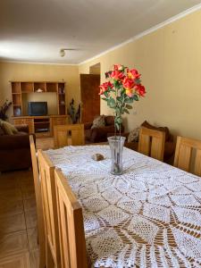 a dining room table with a vase of flowers on it at Casa grande Campestre, Vicuña, Valle del Elqui in Vicuña