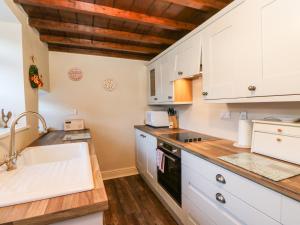 eine Küche mit weißen Schränken und einem Waschbecken in der Unterkunft Myrtle Cottage in Leyburn
