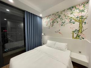 - une chambre avec un lit blanc et une fresque murale sur les arbres dans l'établissement Gavi Home - Luxury Apartment Vinhome Green Bay Mễ Trì Hà Nội, à Hanoï
