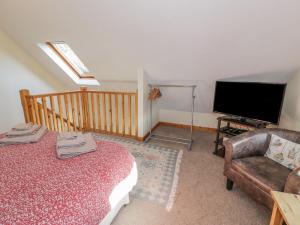 een woonkamer met een bed en een televisie bij Bryn Melyn Artist's Cottage in Llanelltyd