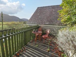 een patio met een tafel, 2 stoelen en een hek bij Bryn Melyn Artist's Cottage in Llanelltyd