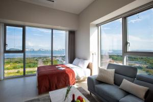 um quarto com uma cama, um sofá e janelas grandes em Blue Ocean Residence Hotel em Incheon