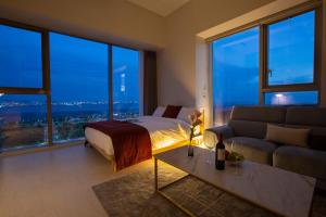 1 dormitorio con cama, sofá y ventanas grandes en Blue Ocean Residence Hotel, en Incheon