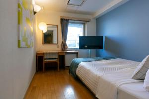 1 dormitorio con 1 cama y escritorio con TV en Hotel Toms, en Tokio