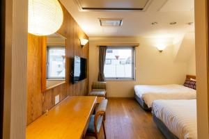 東京にあるホテル トムスのベッド2台とテーブルが備わるホテルルームです。