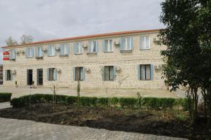 a large brick building with trees in front of it at Hotel AGUNA in Kutaisi