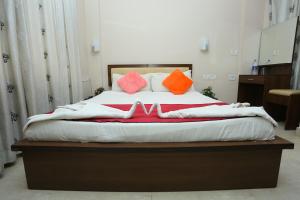 Una cama con almohadas de color naranja y rosa. en Hotel Innate Inn en Alwaye