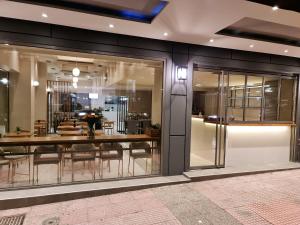 a store front with glass doors and tables and chairs at Hotel @Syngrou Fix in Athens