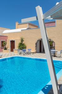 a pool in front of a building with chairs and tables at Hotel Sunrise in Fira