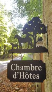 un panneau avec des chevaux à côté d'un arbre dans l'établissement Les Sabots du Parc, à Ermenonville
