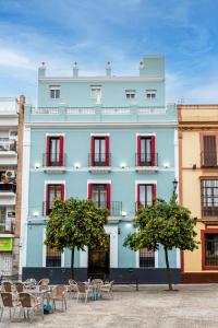 un edificio azul con mesas y sillas delante de él en Hotel Sevilla en Sevilla