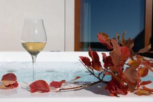 a glass of white wine next to a flower on a table at Encanto Agriturismo & Private SPA in Visogliano