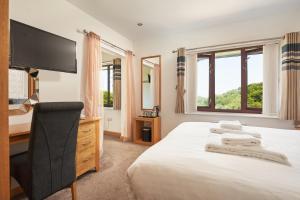 a bedroom with a bed with a television and a chair at The Windmill Inn in Watchet