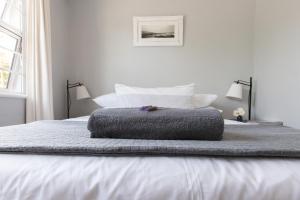 un letto con un cuscino grigio sopra di Surf Way Beach cottage a Città del Capo