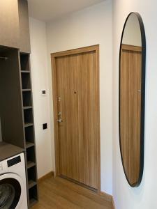 a bathroom with a wooden door and a mirror at Happy Kaunas in Kaunas