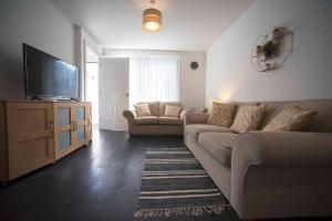 a living room with a couch and a flat screen tv at A Cosy 3-bed Family House in Liverpool sleeps 6 with parking spaces in Liverpool