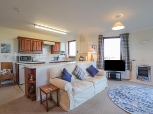 a living room with a couch and a kitchen at Aurora View in Forres