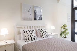 a white bedroom with a bed with two pillows at Effie's cozy old town studios in Rethymno
