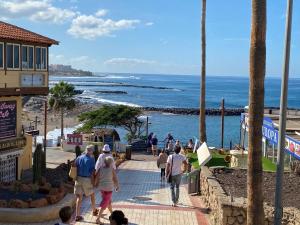 eine Gruppe von Menschen, die einen Bürgersteig am Strand entlang laufen in der Unterkunft Las Flores studio 2 in Playa de las Americas