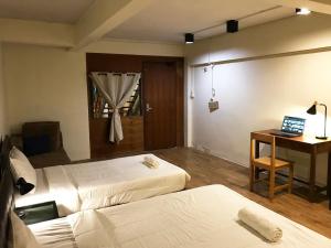 Zimmer mit 2 Betten und einem Schreibtisch mit einem Laptop in der Unterkunft Boundary Hostel and Cafe in Surat Thani