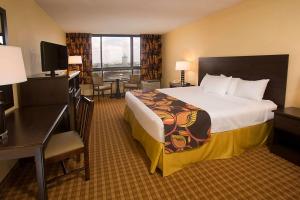 オーランドにあるRamada Plaza by Wyndham Orlando Resort & Suites Intl Driveの大きなベッドとデスクが備わるホテルルームです。
