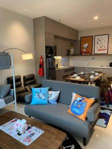 a living room with a blue couch and a kitchen at Genting Geo38 Residence Snoopy Studio in Genting Highlands