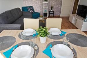 una mesa de comedor con platos blancos y servilletas azules en Panorama View Apartment en Veszprém