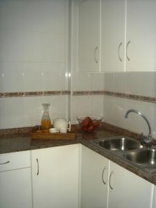 a kitchen with white cabinets and a sink at Apartamentos Margoysa I in Los Alcázares +13 photos