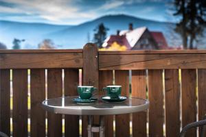 シュクラルスカ・ポレンバにあるSłoneczny Kątのフェンスの上のテーブルに並ぶ緑のコーヒーカップ2杯