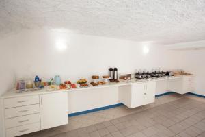 a white kitchen with a counter with food on it at Pousada Villa Grécia in Aracaju
