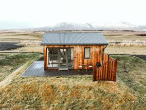 a tiny house on a field with mountains in the background at Austurey Cottages in Laugarvatn