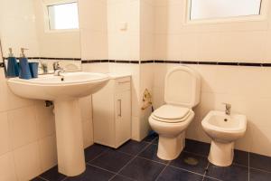a white bathroom with a sink and a toilet at Casa Da Atalaia in Caniço