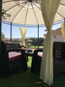 ein Zelt mit Stühlen und einem Tisch mit einem Sonnenschirm in der Unterkunft الكوخ الريفي in Madain Saleh