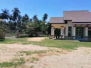 a house with a large yard in front of it at D'Ombak Homestay Pantai Baru in Bachok