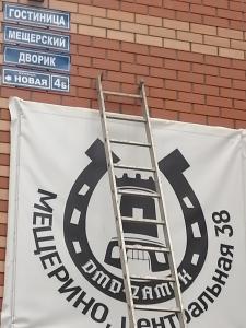 a sign on a brick wall with a ladder at Гостиница Мещерский Дворик in Meshcherino