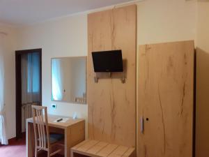 Zimmer mit einem Schreibtisch und einem TV an der Wand in der Unterkunft Hotel Des Alpes in Castione della Presolana
