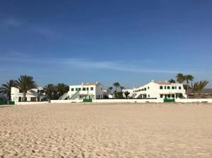 Blick auf den Strand mit Häusern im Hintergrund in der Unterkunft El Sueño - Appartamento fronte spiaggia vista mare in Cotillo