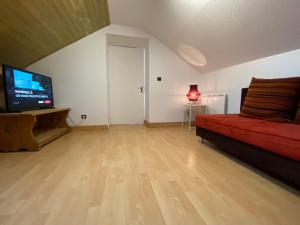een woonkamer met een rode bank en een flatscreen-tv bij Après l'école, appartement de charme in Oz