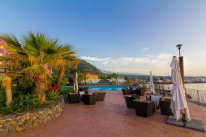 a patio with chairs and umbrellas and a pool at Santa Tecla Palace in Acireale