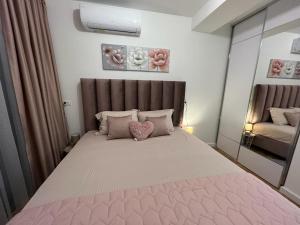 a bedroom with a large bed with pink sheets and pillows at Corall apartment Bar in Bar