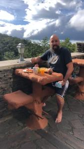 un hombre sentado en una mesa de picnic con comida. en Cabinas Vista Al Golffo, en Monteverde