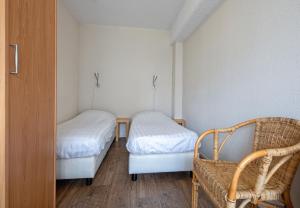 a small room with two beds and a chair at Motel Texel in De Koog
