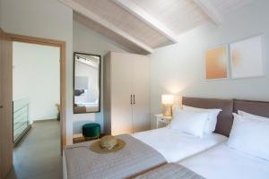a white bedroom with a bed and a mirror at Grappolo Lefkada Villas - Vilana ideal for families and small groups in Apolpaina +37 photos