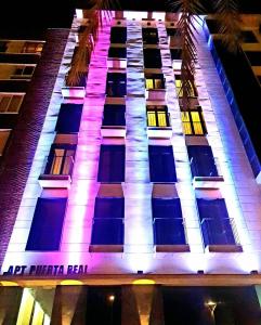 un edificio alto con luces encendidas por la noche en Apartamentos Turísticos Puerta Real en Cartagena