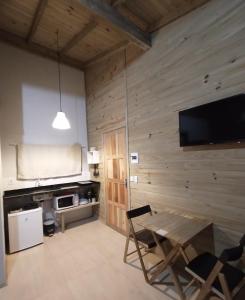 a room with a wooden wall with a table and a tv at SUÍTES PRAIA DO ROSA in Imbituba
