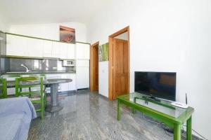 ein Wohnzimmer mit Flachbildfernseher und Tisch in der Unterkunft El Sueño - Appartamento fronte spiaggia vista mare in Cotillo