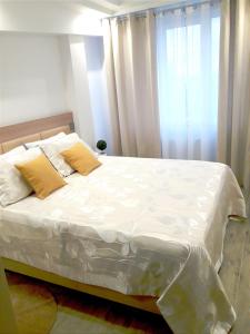 1 dormitorio con 1 cama con sábanas blancas y almohadas amarillas en LIGHT APARTMENT center city CHIȘINĂU, en Chişinău