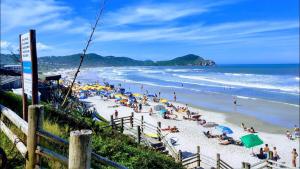 a beach with a bunch of people sitting on the sand at SUÍTES PRAIA DO ROSA in Imbituba