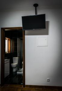 a bathroom with a toilet and a tv on the wall at Hostel Encostas Do Douro in Marco de Canaveses